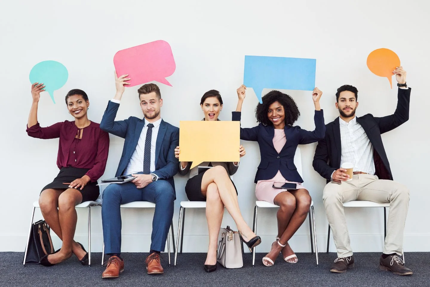 employees holding paper cutouts of speech bubbles over their heads
