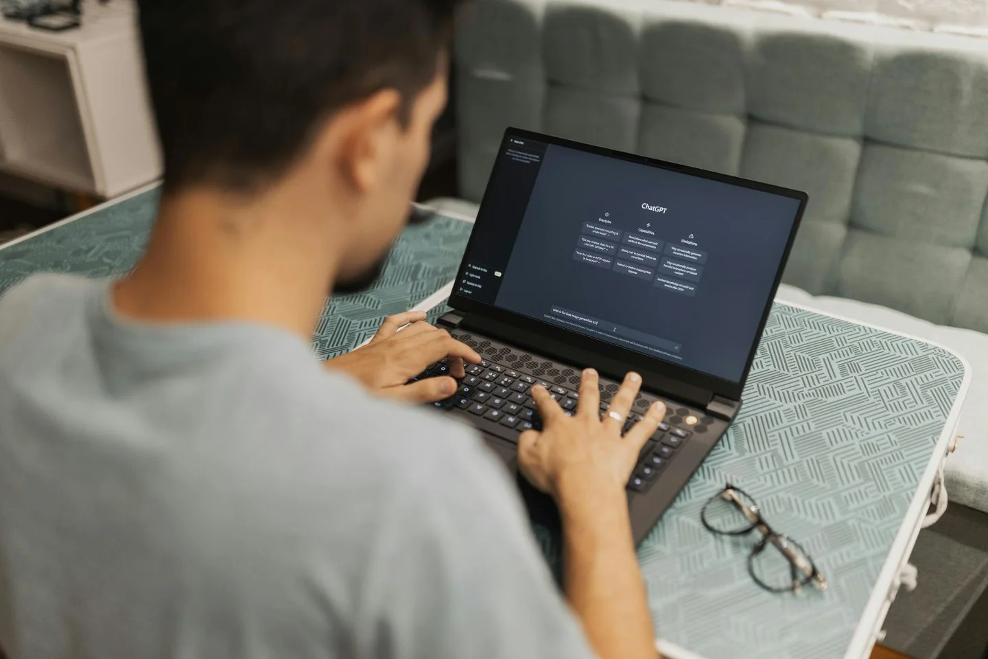 over the shoulder of a person with a laptop on their lap, using chatgpt