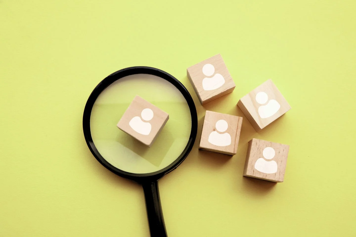magnifying glass over wooden cubes with user icons printed on them