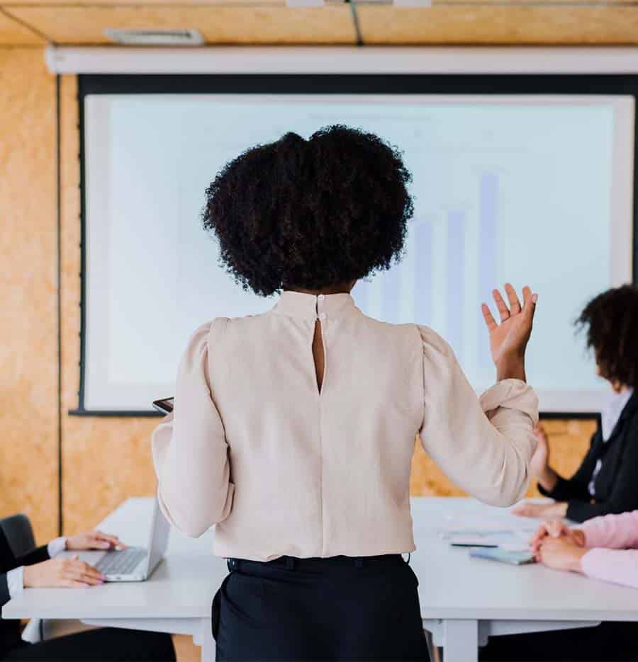 from behind, a woman stands at the head of a conference table